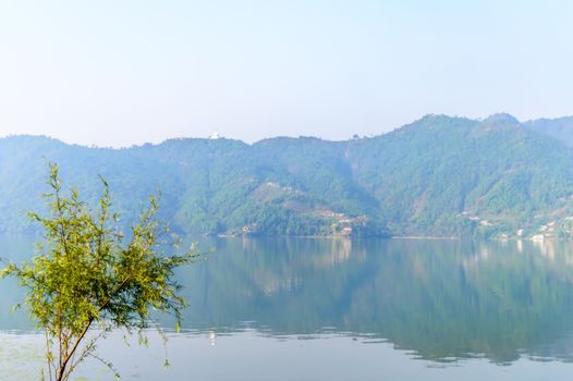 Photograph of autumn colourful lake mountain with clear sky. Wide angle landscape of Pokhara Lake at Kathmandu Nepal. Vintage film look. Vacation Freedom, Simplicity Concept.