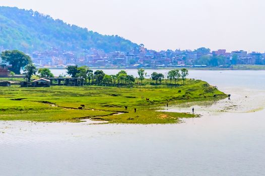Photograph of winter season: A colourful lake, mountain, clear sky and farm land. Wide angle landscape of Pokhara Lake at Kathmandu Nepal. Vintage film look. Vacation Freedom, Simplicity Concept.