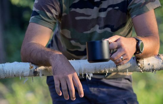 Man drinking coffee on fenced ranch in morning 