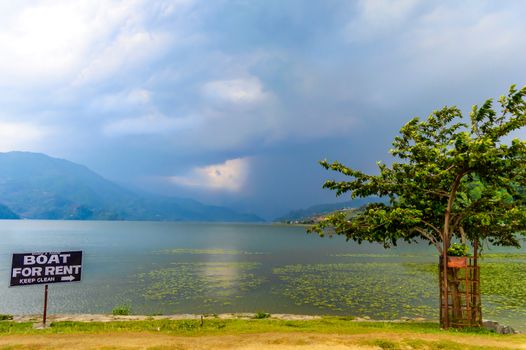 Photograph of cloud, lake, mountain, tree and reflexion in water Near Pokhara Lake at Kathmandu Nepal. Snap in portrait, landscape, wide screen. Vintage film look. Nature Freedom, Environment Concept.