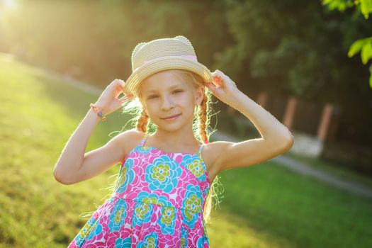 Pretty teen girl posing in hat among summer and sunset