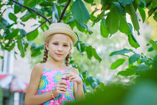 Girl in hat among green tree with bubbles