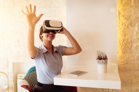 Smiling businesswoman using virtual reality glasses in a cafe.