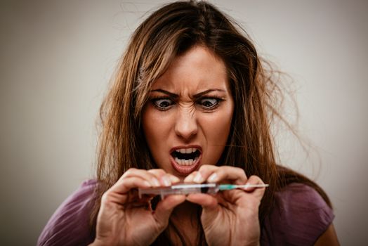 Portrait of a young female drug addiction, holding syringe with drugs.