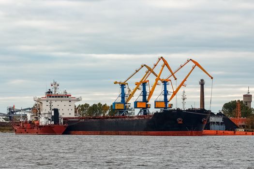 Black cargo ship loading in the port of Riga, Europe