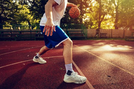 Unrecognizable young street basketball player showing his skills on court. 