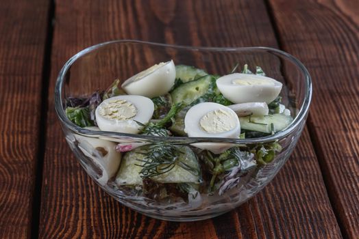 Salad with vegetables and quail eggs on old wooden dark background