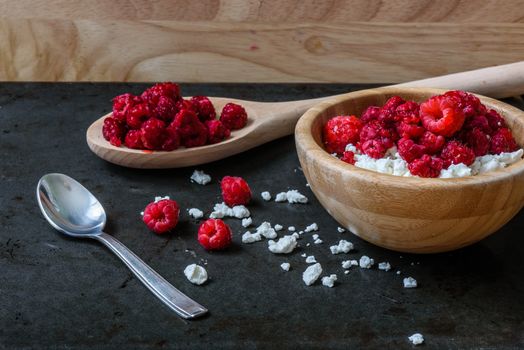 Bowl of cottage cheese with raspberries for breakfast with scattered berries and grains of curd. space for text