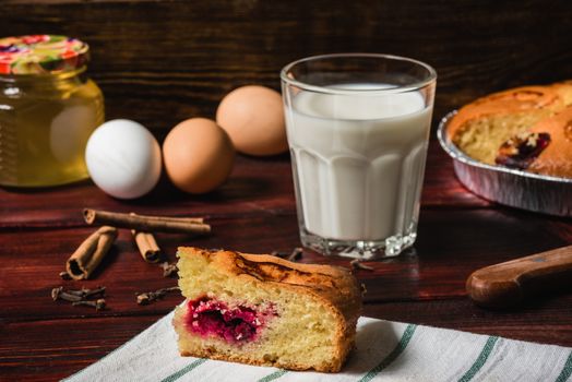 Sweet breakfast with cherry cake and glass of milk and ingredients lie on the table.