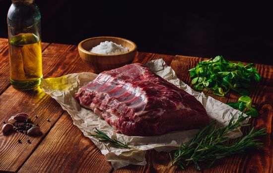 Raw Ribs with Greens and Spices on Wooden Table.