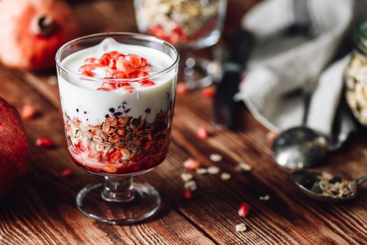 Pomegranate Parfait with Ingredients on Backdrop. Series on Prepare Healthy Dessert with Pomegranate, Granola, Cream and Jam.