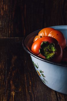 Ripe Persimmons in Metal Blue Bowl on Rustic Table
