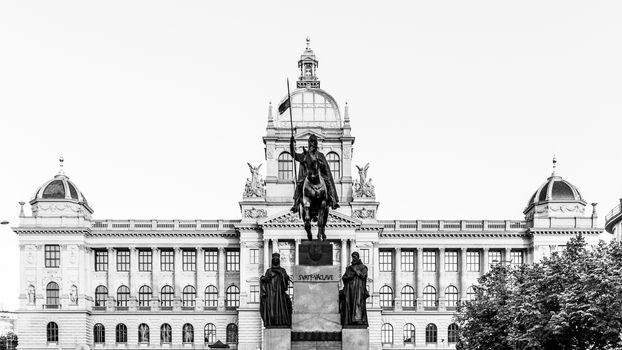 The bronze equestrian statue of St Wenceslas at the Wenceslas Square with historical Neorenaissance building of National Museum in Prague, Czech Republic. Black and white image.