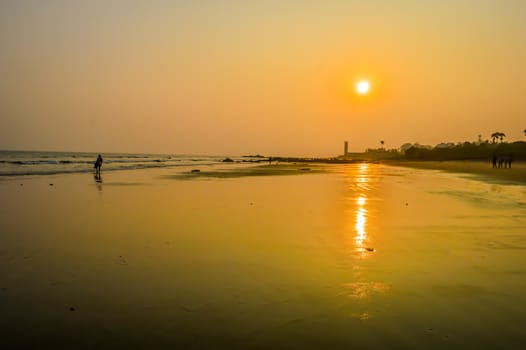 Beautiful sea shore at sunrise or sunset sunset Wild Empty Tropical beach, orange sky, sunlight reflextions on the shore at sunset time on a sunny day in in as landscape style may be used as a background, wallpaper, screen saver banner Travel vacation concept. The image is exciting, bright, sensational, tranquil, calm, stunning