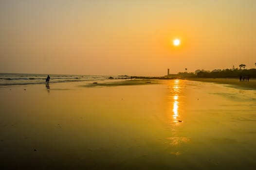 Beautiful sea shore at sunrise or sunset sunset Wild Empty Tropical beach, orange sky, sunlight reflextions on the shore at sunset time on a sunny day in in as landscape style may be used as a background, wallpaper, screen saver banner Travel vacation concept. The image is exciting, bright, sensational, tranquil, calm, stunning