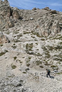 Hiker walking on a path in Dolomites, Italy