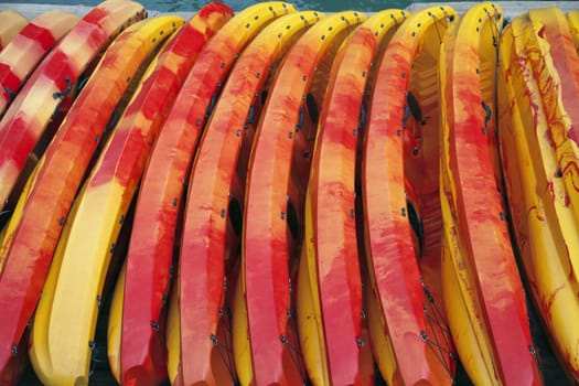 Many sea kayaks laying in a row, ready for a tour