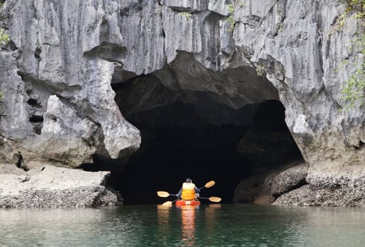 Cayakers entering a sea cave in Ha Long bay