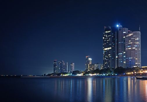 A long exposure of nigh cityscape at the beach. Light from building is reflect on the water.