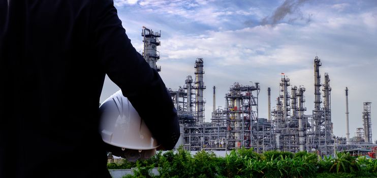 The engineer is holding a safety helmet on large industry background. The construction manager on the industry background.