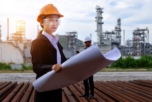 The engineer is checking a layout on large industry background. The construction manager on the industry background.