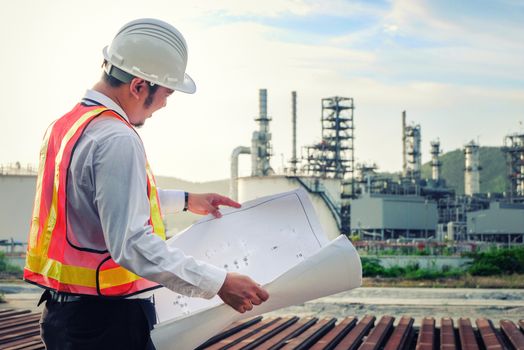 The engineer is checking a layout on large industry background. The construction manager on the industry background.