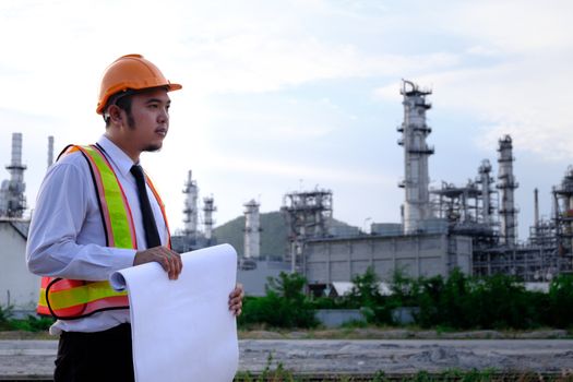 The engineer is checking a layout on large industry background. The construction manager on the industry background.