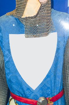 Medieval knight armor with chain mail and coat of arms on blue shirt