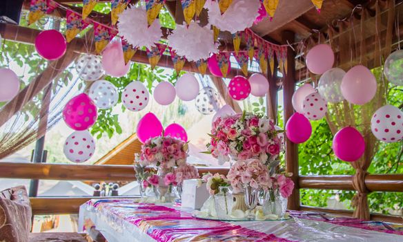 Pink girl birthday party with decorated table, flowers and balloons