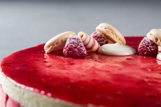 Decoration with raspberries, chocolates and biscuits on a cake