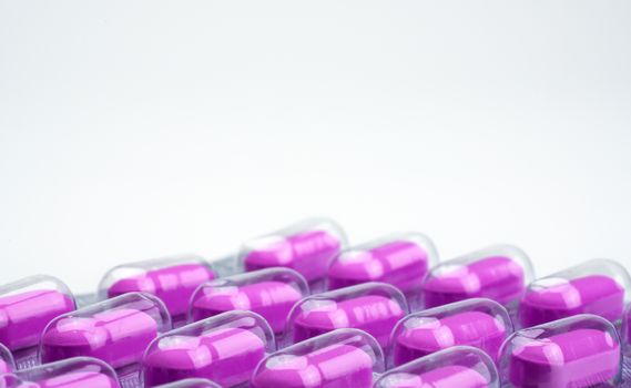 Macro shot of purple caplets pills in blister pack on white background. Mild to moderate pain management. Pain killer medicine. Pills for treatment heart broken concept. NSAIDs. Pharmaceutical packaging industry. Pharmacy background. Global healthcare concept.