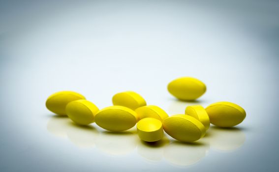Yellow oval tablet pills with shadows on white background with beautiful creative pattern and copy space for text. Mild to moderate pain management. Pain killer medicine. NSAIDs drug. Pharmaceutical industry. Pharmacy background. Global healthcare concept.