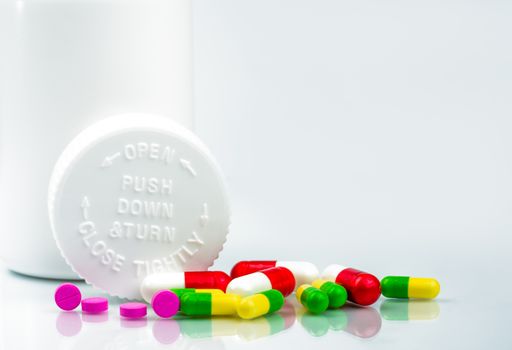 Colorful pills on white background and childproof bottle with blank label and copy space. Pharmacy department in the hospital concept. Drug store concept. Pharmaceutical industry. Pharmacy background. Pharmacology and drug interactions concept. Global healthcare.