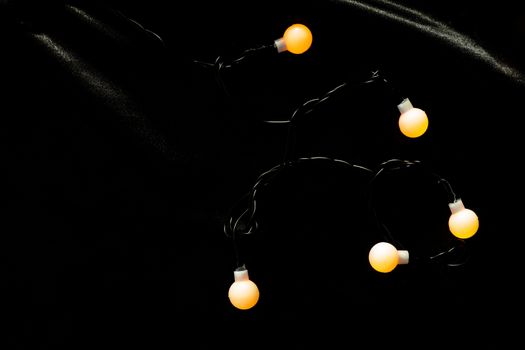 Decoration lamp light with on black wool. Bulb warm light on black and shiny frieze fabric.