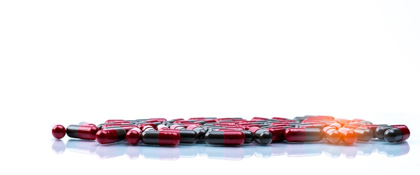Pile of red and grey capsule pills isolated on white background with copy space. Flunarizine : drug for migraine prophylaxis treatment. Global healthcare concept. Pharmaceutical industry. Pharmacy background.