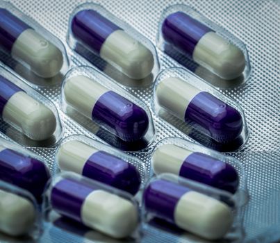 Fluconazole : Antifungal medicine. Full frame picture of purple, white capsule pills. Healthcare concept. Medicine pills can cause liver damage. Pharmaceutical industry background.