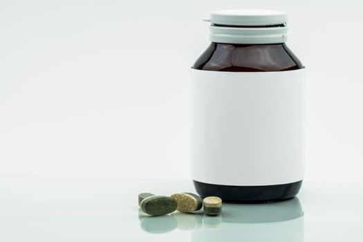 Vitamins, supplements and minerals dual layer tablets pills and medicine amber glass bottle with blank label isolated on white background with copy space. Use for vitamins and supplements advertising.