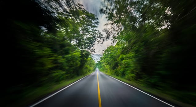 Empty asphalt road and speed motion blur on highway in summer with green trees forest at countryside