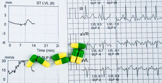 EKG or ECG (Electrocardiogram) graph report paper. EST ( Exercise Stress Test ) result and green-yellow capsule pills. Package promotion for heart check up in senior or elderly people concept.