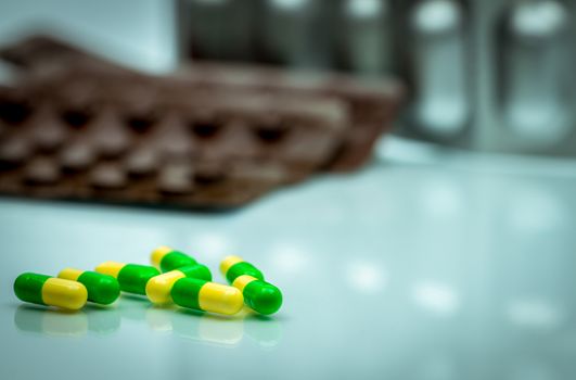 Green, yellow tramadol capsule pills on blurred blister pack background with copy space. Cancer pain management. Opioid analgesics. Drug abuse in teenage in Thailand. Pharmaceutical industry. Pharmacy background. Global healthcare concept.