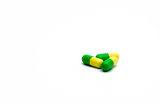 Green, yellow tramadol capsule pills on white background with shadows and copy space. Cancer pain management. Opioid analgesics. Drug abuse in teenage in Thailand. Pharmaceutical industry. Pharmacy background. Global healthcare concept.