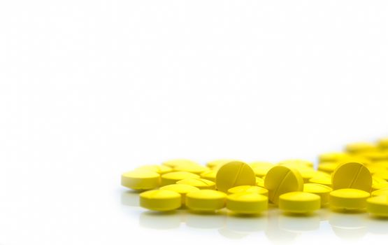 Yellow tablets pills isolated on white background with copy space. Pile of medicine. Painkiller tablets pills. NSAIDs drug. Pharmaceutical industry. Pharmacy background. Global healthcare. Health budgets and policy.