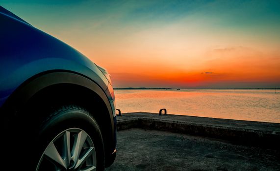 Blue compact SUV car with sport and modern design parked on concrete road by the sea at sunset. Environmentally friendly technology. Business success concept. Hybrid car. Automotive industry.