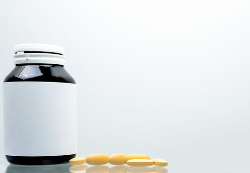 Tablets pills of vitamin C 1,000 mg on white background and amber bottle with blank label and copy space for text. Vitamin and supplement concept. Antioxidant. Pharmaceutical industry. Pharmacy background. Global healthcare.