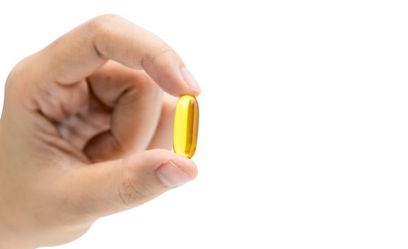 Yellow fish oil capsule pills in Asian woman hand isolated on white background with copy space. Cardiovascular care and joint care. Vitamins and supplements concept. Global healthcare concept.