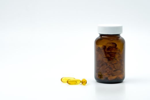 Yellow fish oil capsule pills with amber glass bottle with blank label on the table with copy space for text. Vitamins and supplements for heart care and joint care. Source of omega 3, EPA and DHA. Pharmaceutical industry. Global healthcare concept.