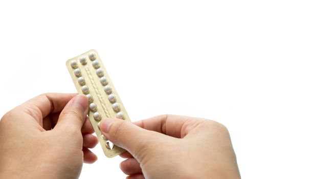 Woman hand taking birth control pills. Asian adult woman holding pack of contraceptive pills isolated on white background with clipping path. Choosing family planning with birth control pill concept