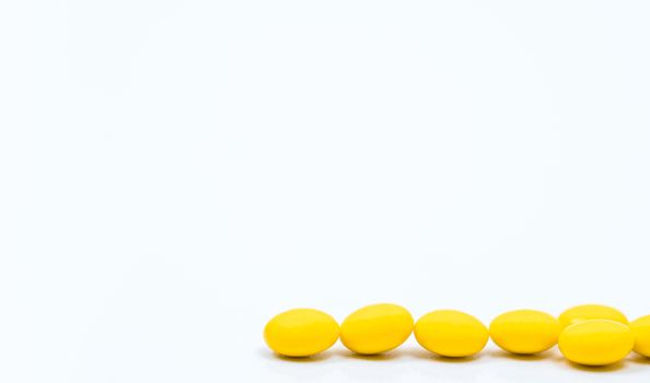 Yellow sugar coated tablets pills on white background with copy space. Medicine for treatment constipation. Pharmaceutical industry. Pharmacy background. Global healthcare concept. Health budgets and policy.