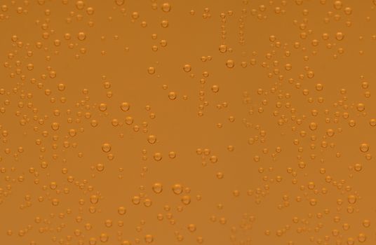 Macro shot of orange effervescent bubbles of calcium and vitamin C effervescent tablets in transparent glass. Orange color texture background.