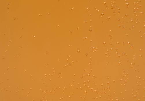 Macro shot of orange effervescent bubbles of calcium and vitamin C effervescent tablets in transparent glass. Orange color texture background.